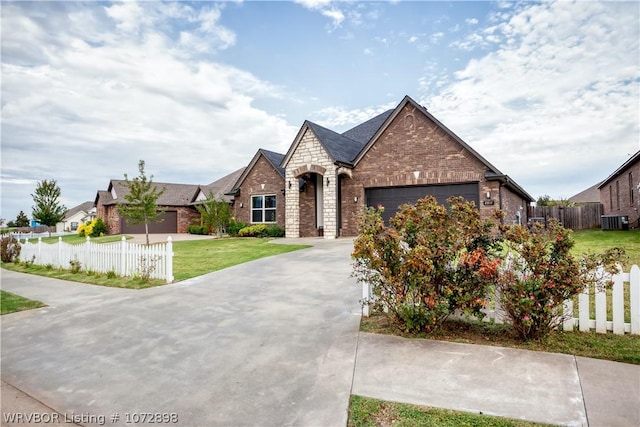 view of front of home with cooling unit, a front yard, and a garage