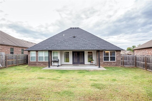 back of property with a yard and a patio