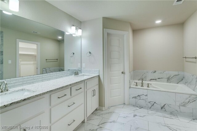 bathroom with tiled bath and vanity