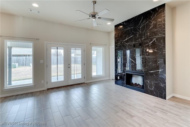 unfurnished living room featuring french doors, ceiling fan, and a premium fireplace