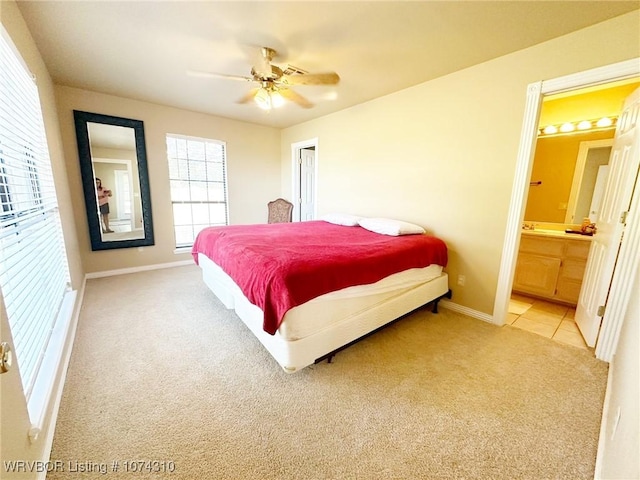 carpeted bedroom featuring multiple windows, ensuite bathroom, and ceiling fan