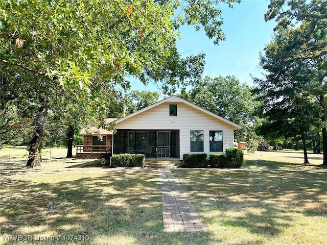 view of front of house with a sunroom and a front yard