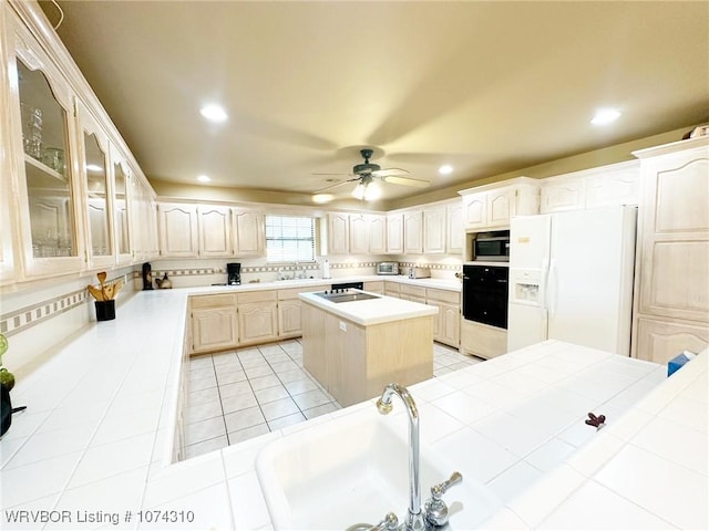 kitchen with ceiling fan, tile counters, a center island, light tile patterned flooring, and black appliances