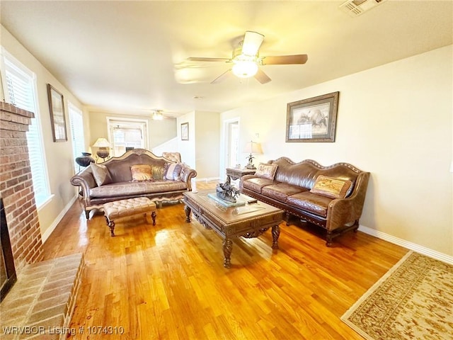 living room featuring ceiling fan, a fireplace, and hardwood / wood-style flooring