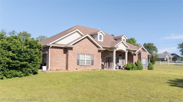 view of front of home with brick siding, a front lawn, and fence