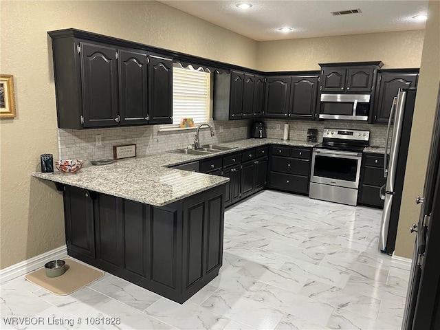1610 Tiger Lily Ct, Greenwood, AR 72936 - kitchen with appliances with stainless steel finishes, a peninsula, tasteful backsplash, light marble finish flooring, and a textured wall