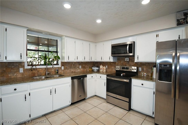 kitchen featuring sink, dark stone countertops, white cabinets, decorative backsplash, and stainless steel appliances