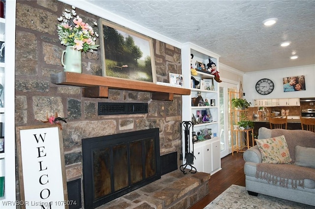 living room featuring crown molding, a fireplace, dark wood-type flooring, and a textured ceiling