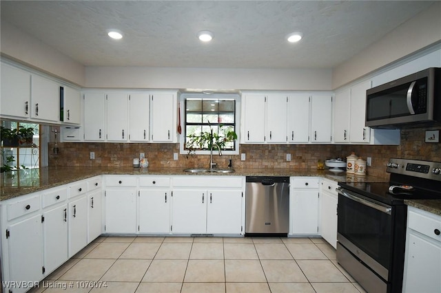 kitchen featuring stainless steel appliances, sink, dark stone countertops, and white cabinets