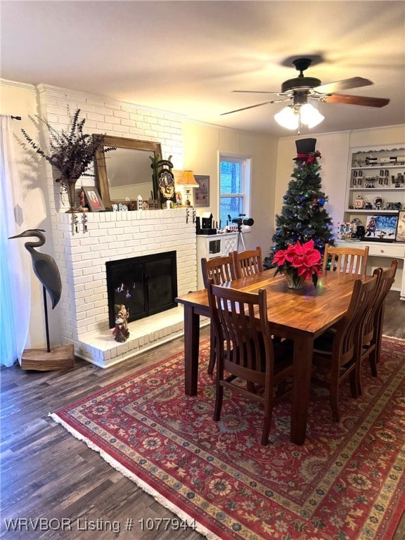 dining area with ceiling fan, wood-type flooring, a fireplace, and brick wall