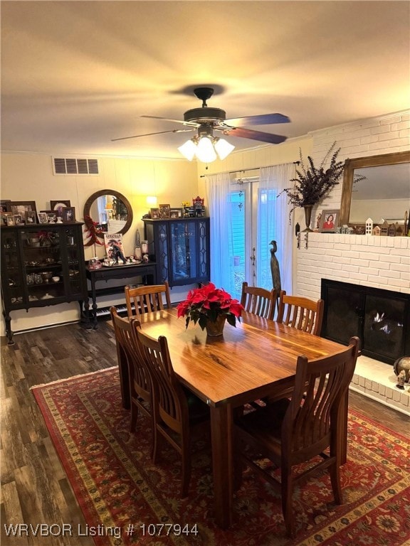 dining space featuring ceiling fan, a fireplace, and dark wood-type flooring