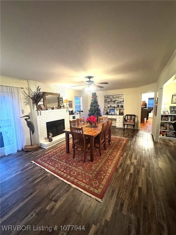 dining area featuring ceiling fan, dark hardwood / wood-style floors, and a fireplace