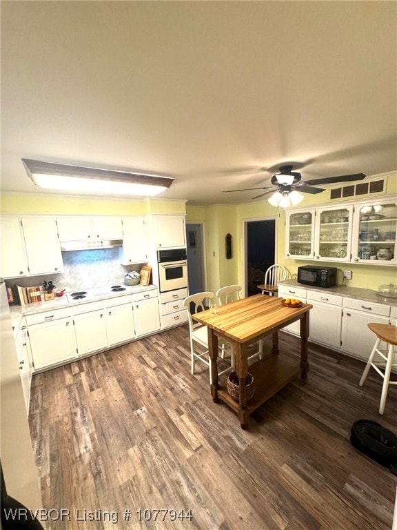 kitchen with white cabinets, oven, and dark hardwood / wood-style flooring