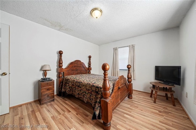 bedroom with light wood-type flooring and a textured ceiling