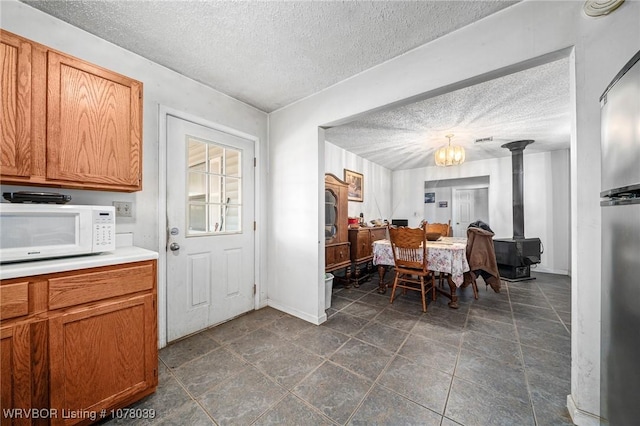 469517 E 1060th Rd, Muldrow, OK 74948 - dining space with baseboards, a wood stove, a textured ceiling, and a chandelier
