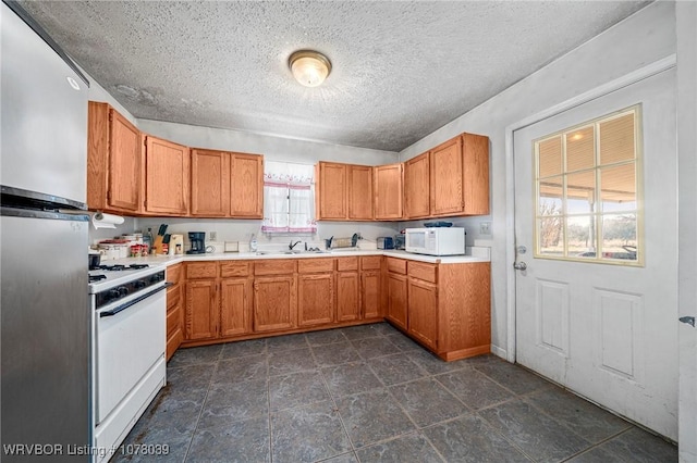 kitchen featuring a textured ceiling, sink, and white appliances