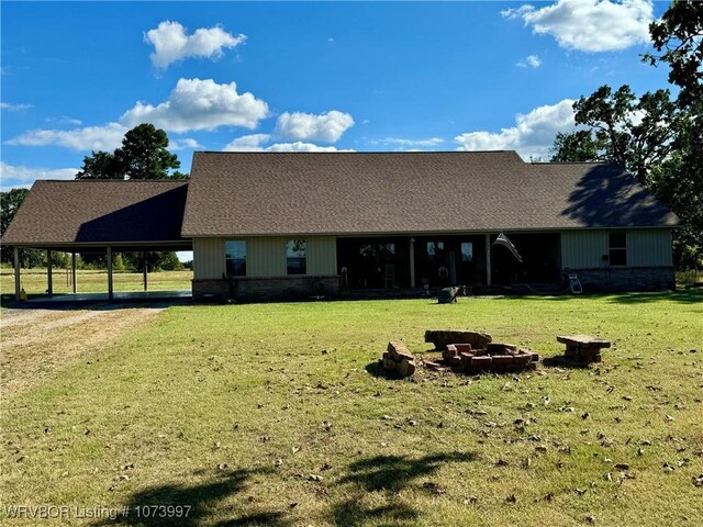 view of front of home featuring a carport, an outdoor fire pit, and a front lawn