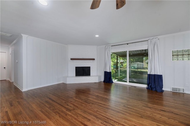 unfurnished living room with dark hardwood / wood-style floors, a brick fireplace, ceiling fan, and crown molding