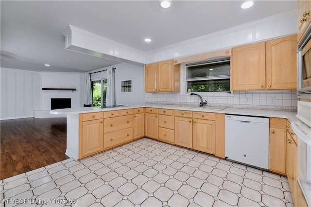 kitchen featuring light brown cabinetry, sink, white dishwasher, and a fireplace