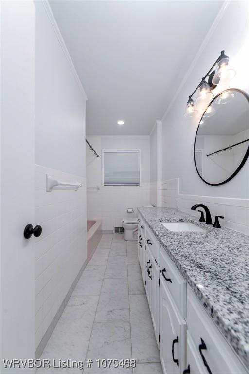 full bathroom with vanity, shower / washtub combination, toilet, ornamental molding, and tile walls