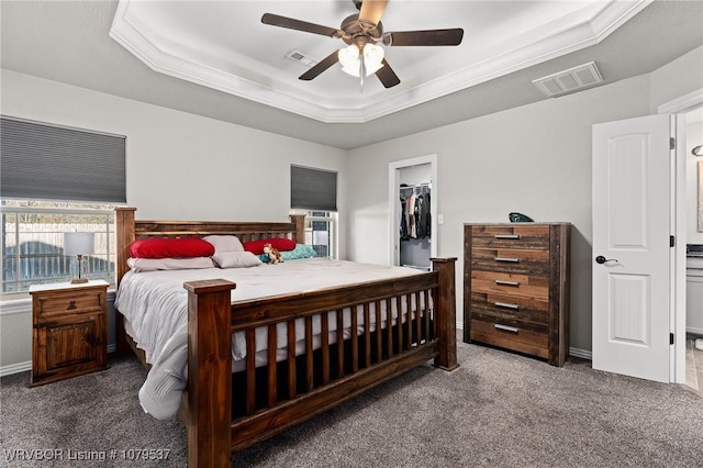 bedroom with visible vents, a walk in closet, a raised ceiling, and carpet floors