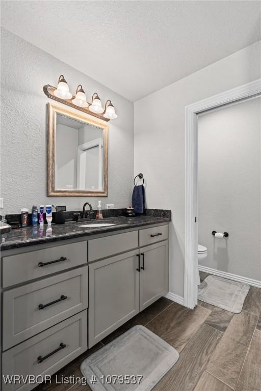 bathroom featuring baseboards, toilet, and vanity