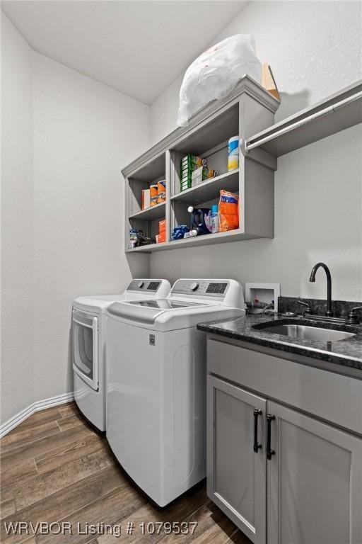 laundry area featuring baseboards, dark wood finished floors, cabinet space, a sink, and washer and dryer