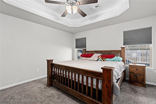 carpeted bedroom with a tray ceiling, baseboards, visible vents, and a ceiling fan