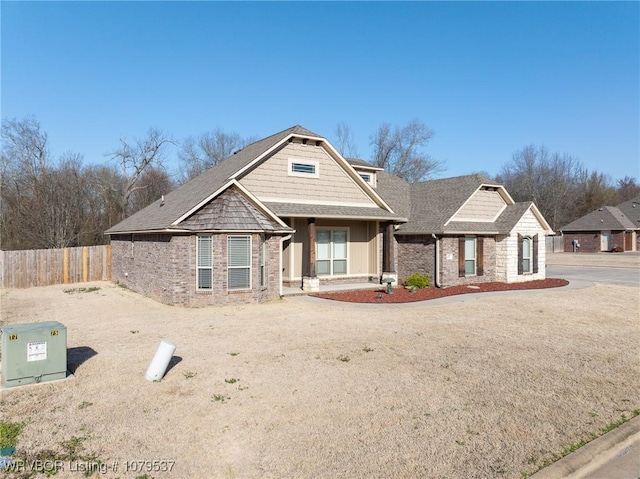 craftsman house featuring brick siding, roof with shingles, and fence