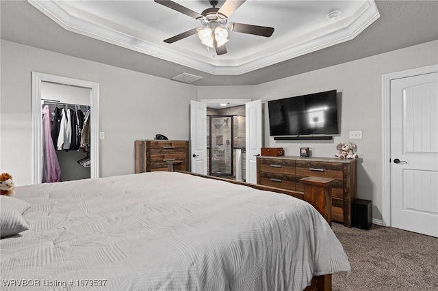 bedroom with a ceiling fan, carpet, visible vents, a tray ceiling, and a spacious closet