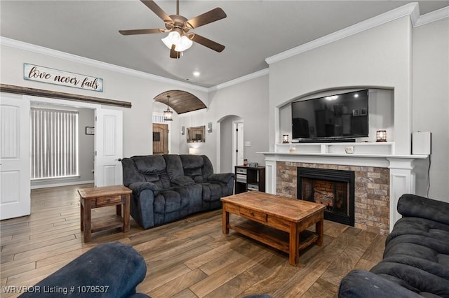 living room featuring a fireplace, wood finished floors, arched walkways, and ornamental molding