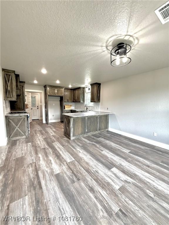 2948 N Hwy 282, Van Buren, AR 72956 - kitchen featuring a peninsula, wood finished floors, dark brown cabinets, a textured ceiling, and light countertops