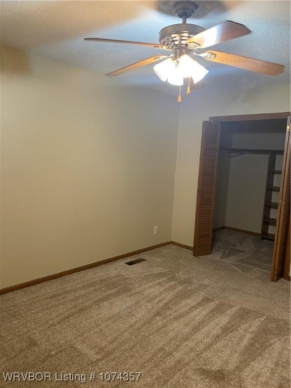 carpeted empty room featuring ceiling fan and a textured ceiling