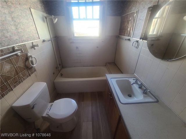 full bathroom featuring tile walls, tiled shower / bath combo, vanity, wood-type flooring, and toilet