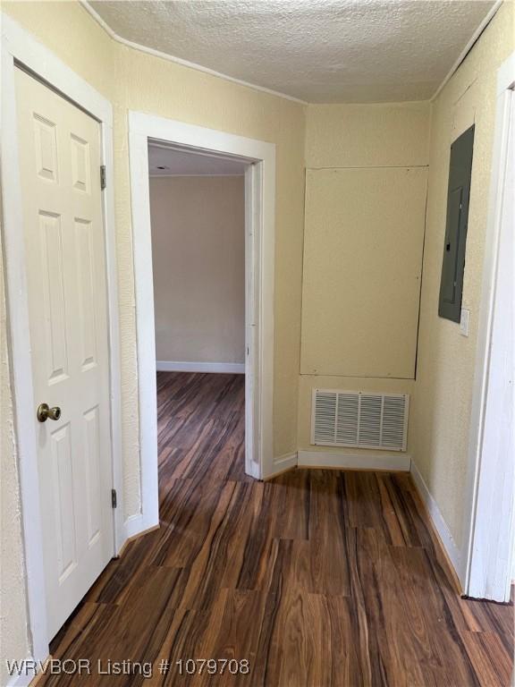 710 S Mulberry St, Sallisaw, OK 74955 - interior space featuring wood finished floors, baseboards, visible vents, electric panel, and a textured ceiling
