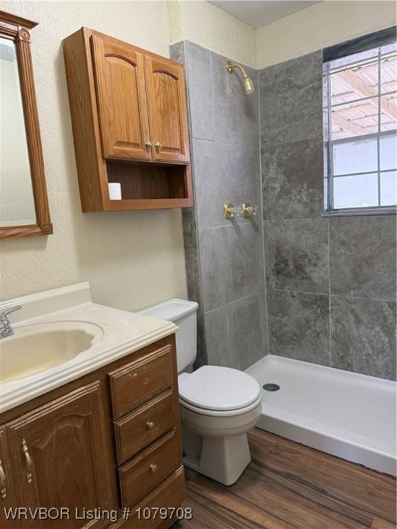 710 S Mulberry St, Sallisaw, OK 74955 - bathroom with toilet, wood finished floors, tiled shower, a textured wall, and vanity