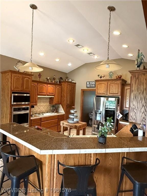 417 N Rattlesnake Rd, Charleston, AR 72933 - kitchen with appliances with stainless steel finishes, a breakfast bar, vaulted ceiling, brown cabinetry, and backsplash