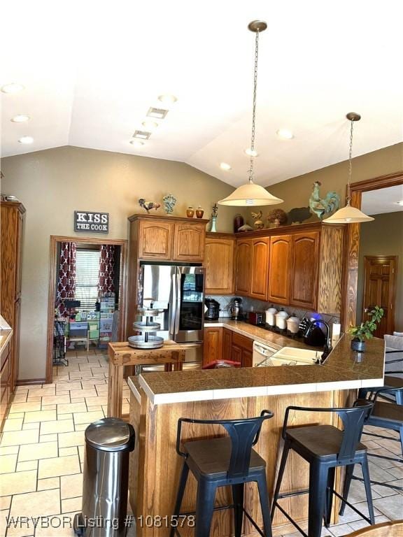 417 N Rattlesnake Rd, Charleston, AR 72933 - kitchen with stainless steel fridge, vaulted ceiling, a breakfast bar area, brown cabinets, and pendant lighting