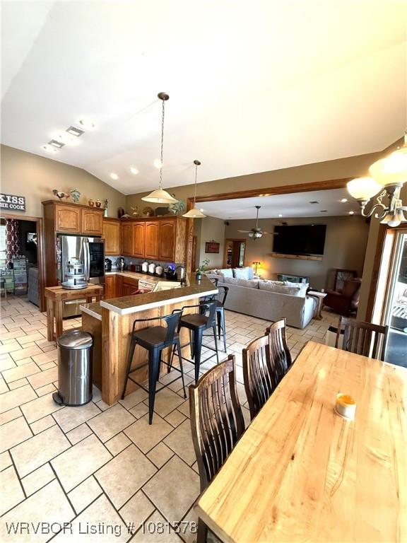 417 N Rattlesnake Rd, Charleston, AR 72933 - kitchen featuring stainless steel fridge, a kitchen breakfast bar, pendant lighting, vaulted ceiling, and brown cabinetry