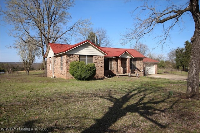 view of front facade with driveway, metal roof, a front yard, a garage, and brick siding