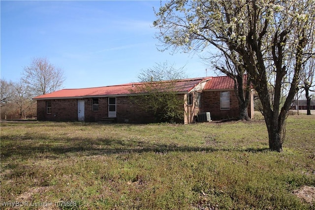 back of house featuring metal roof, a lawn, and cooling unit
