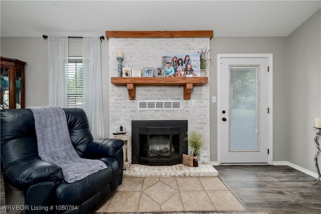 living area featuring baseboards, visible vents, a large fireplace, and wood finished floors