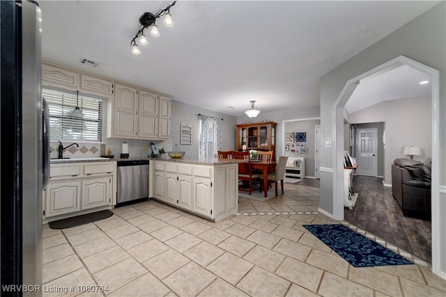 kitchen featuring light tile patterned floors, visible vents, a sink, a peninsula, and stainless steel appliances