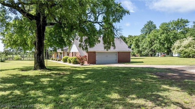 exterior space featuring metal roof, brick siding, driveway, and a front yard