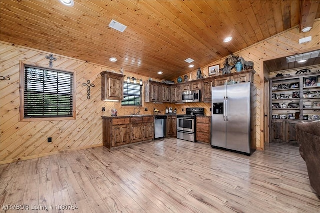 kitchen featuring lofted ceiling, light wood-style flooring, wooden walls, dark countertops, and appliances with stainless steel finishes