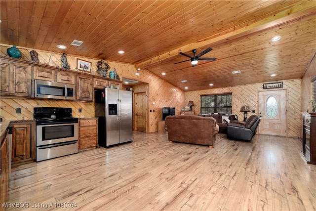 kitchen with wooden walls, light wood finished floors, appliances with stainless steel finishes, and visible vents