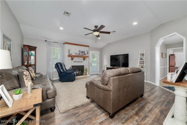 living area with wood finished floors, visible vents, vaulted ceiling, arched walkways, and a ceiling fan