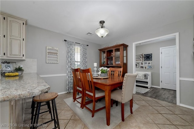 dining space with light tile patterned flooring, baseboards, and visible vents