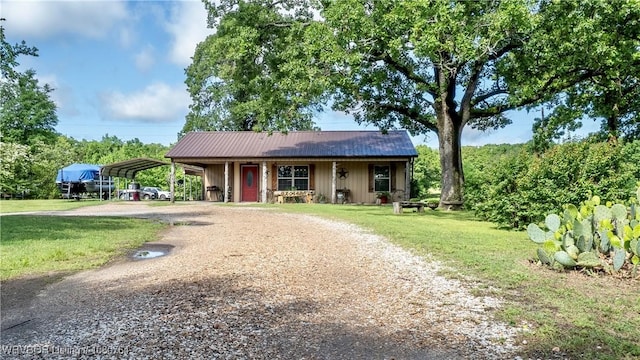 ranch-style home featuring covered porch, dirt driveway, a front yard, and a carport