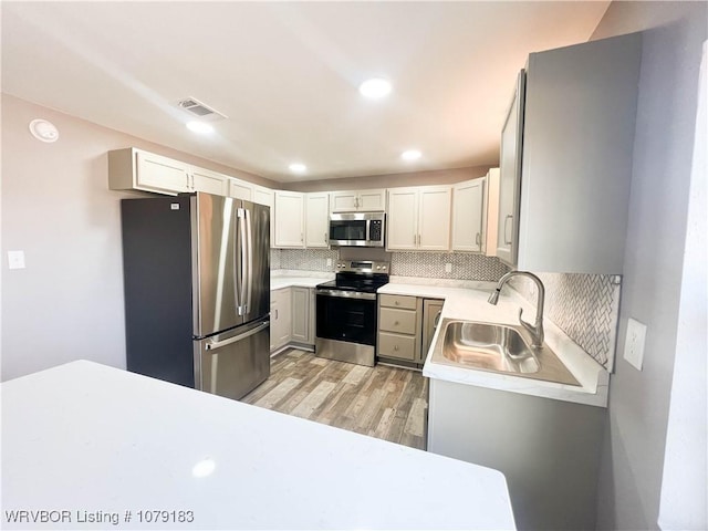 kitchen with light countertops, visible vents, appliances with stainless steel finishes, white cabinetry, and a sink